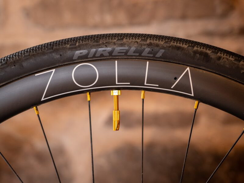 zolla-rim-pirelli-2025 Close-up of a Zolla rim with a Pirelli tyre against a stone wall